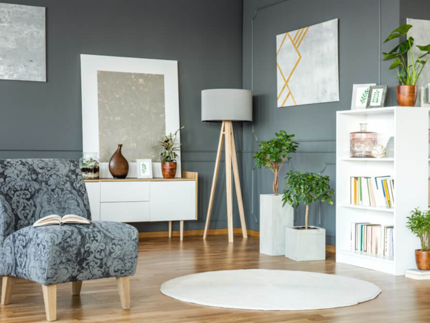 Lush_reading_nook_grey_wall_timber_floorboards_grey_chair_plants_white_bookcase_artwork
